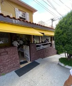 Fachada amarela do Restaurante La Finestra com toldo e muro de pedra na Rua Bartira