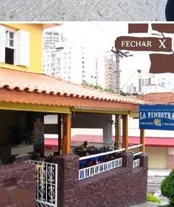 Varanda do La Finestra com toldo amarelo e grade, vista da calçada